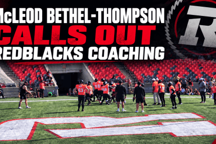 Ottawa REDBLACKS players on the field at TD Place during warmups, with red and black stadium seating in the background.